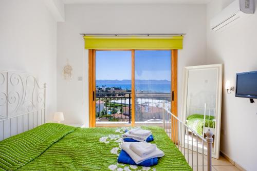 a bedroom with a green bed and a large window at Argaka Sunset Villa in Argaka
