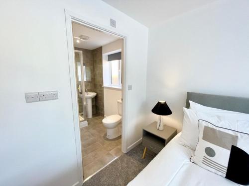 a bedroom with a bed and a bathroom with a toilet at NEW Bungalow - near Quays - Ample Free Parking - Wi-Fi in Gloucester