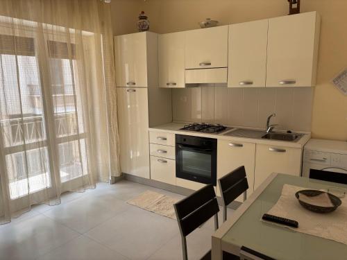 een keuken met witte kasten en een tafel met stoelen bij Casa Vacanza Gallipoli 1D in Gallipoli