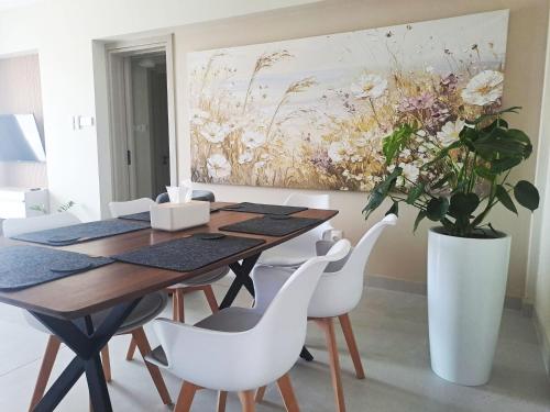 a dining room with a table and chairs and a painting at Sea View Floral Suite - Swimming pool- 2 bedroom in Larnaca