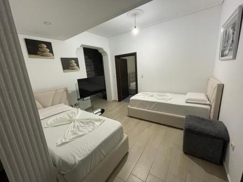 un dormitorio con dos camas y un televisor en White Villa, en Sarandë