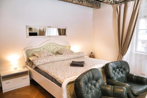a bedroom with a bed and two leather chairs at At the Blue Lion & Parking Assistance in Prague