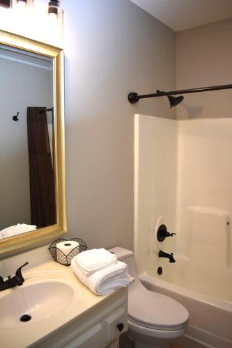 a bathroom with a sink and a mirror and a toilet at Cozy 3BR-3BA Home Near Zona Rosa Shopping and Dining in Kansas City