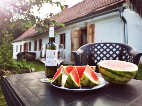 a table with a plate of watermelon and a bottle of wine at Ubytovanie Domček Paradajz in Banská Štiavnica