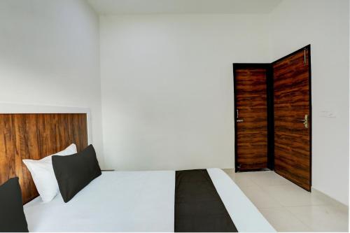a bedroom with a white bed and a wooden door at Hotel O Rajhans in Gurgaon
