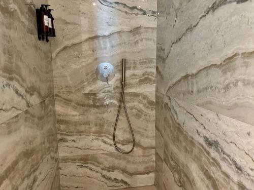 a shower in a bathroom with a stone wall at Comfy Studios Hotel in Benalmádena