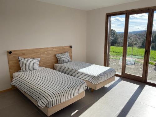 two beds in a room with a large window at Moto Albergue Farango FOR MOTORBIKERS ONLY - SOLO PARA MOTEROS in Benabarre