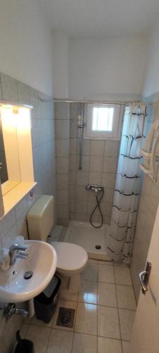 a bathroom with a sink and a shower and a toilet at KANALI HOLIDAYS APARTMENT 2 in Kanali