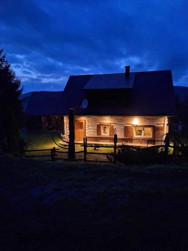 a house with a fence in front of it at night at Chatka na Lipowych Wzgórzach in Marcówka