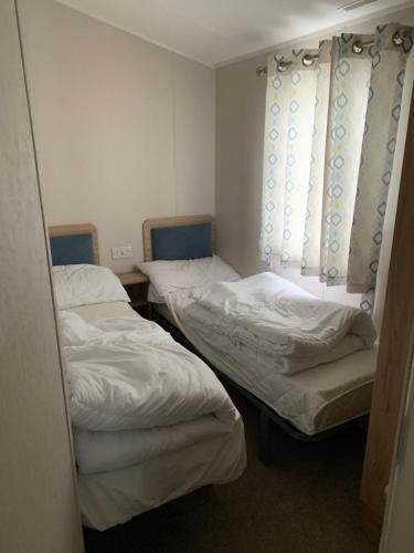 a room with three beds and a window at Sharleen&Peters Caravan in Scratby