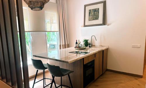 a kitchen with a counter with two chairs and a sink at Comfy Studios Hotel in Benalmádena