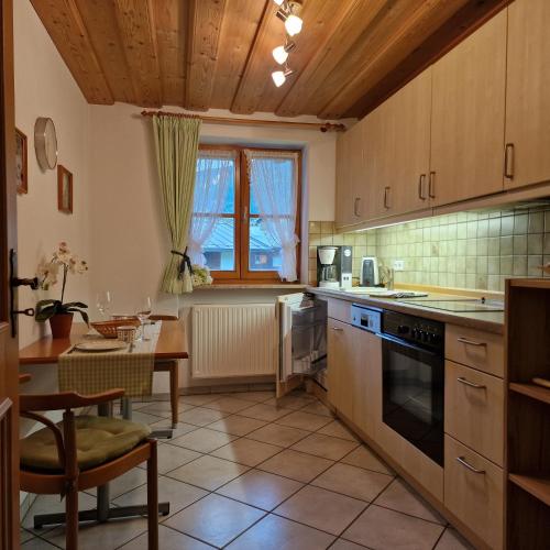 a kitchen with wooden cabinets and a table and a dining room at Ferienwohnung Springl in Schönau am Königssee