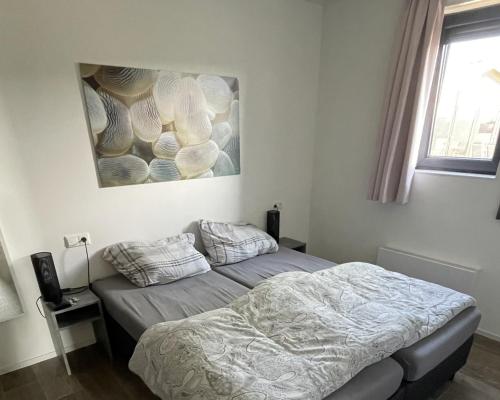 a bedroom with a bed and a painting on the wall at Enkhuizer Strandchalet Nr 257 in Enkhuizen