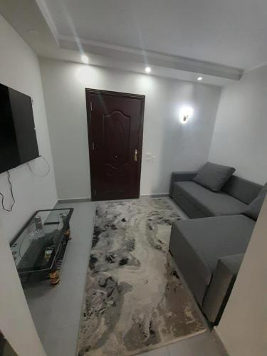 ein Wohnzimmer mit einem Sofa, einem Tisch und einer Tür in der Unterkunft شالية في كمباوند سكانديك عرابيا in Hurghada