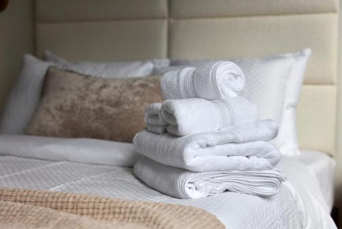 a pile of towels sitting on top of a bed at Sunny 2BR Loft • Work Relax Minutes to NYC in Hoboken