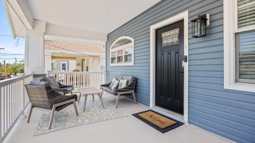 Modern Coastal Comfort - 3 Bedroom Condo with Balcony في أوشن سيتي: بيت أزرق مع شرفة وكراسي وباب