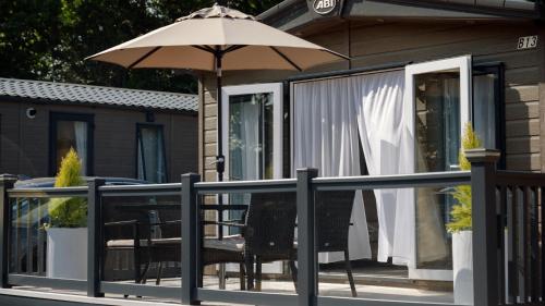 a balcony with a table and an umbrella at New Forest Retreat on a Holiday Park in New Milton
