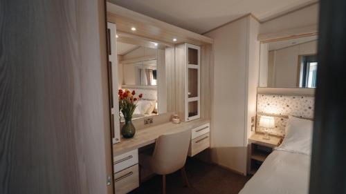 a bedroom with a desk and a bed and a mirror at New Forest Retreat on a Holiday Park in New Milton