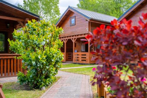 a house with a pathway leading to a house with flowers at ROSSA - Domki Letniskowe in Międzywodzie