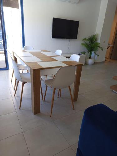 a wooden table with white chairs and a flat screen tv at Appartement Costa Mar Martil in Martil