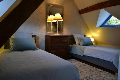 a attic bedroom with two beds and a mirror at Gîte de charme proche du Zoo Beauval et Châteaux in Pontlevoy