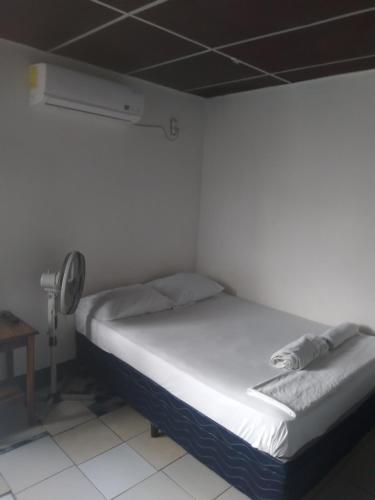 a white bed in a room with a fan at Hostal don Frank in San Carlos
