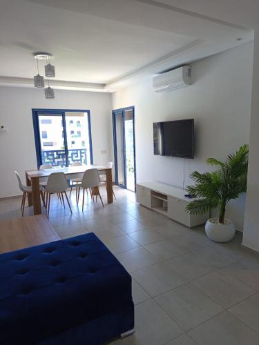 a living room with a table and a tv on a wall at Appartement Costa Mar Martil in Martil