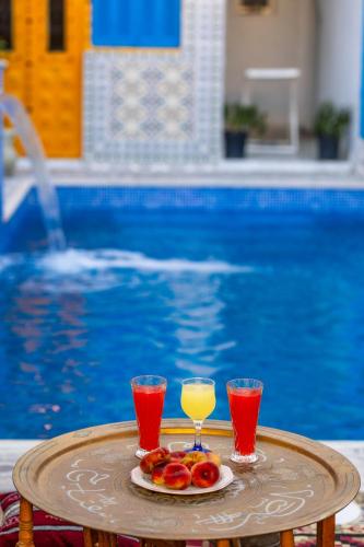 a tray with two glasses of juice and a plate of fruit at BDar Stay Maison d'hôtes avec piscine et rooftop à Tozeur, à 10 min de la Médina in Tozeur