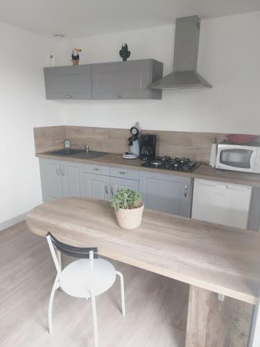 une cuisine avec une table en bois et une chaise dans l'établissement Petite maison au calme, à Le Mesnil-Germain