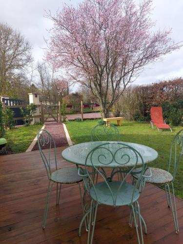 une table et des chaises assises sur une terrasse en bois dans l'établissement Petite maison au calme, à Le Mesnil-Germain