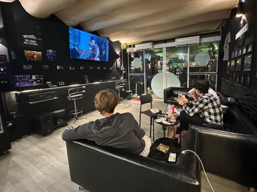 a group of people sitting in a bar watching tv at Andaman Genetics 420 Rooms in Ao Nang 