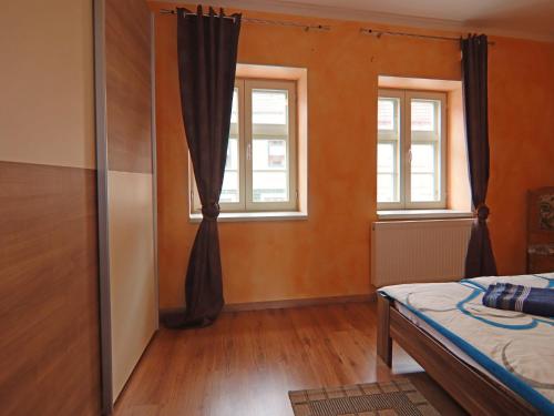 a bedroom with a bed and two windows at Ferienwohnung Kogge im Zentrum von Röbel in Röbel