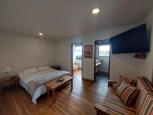 a bedroom with a bed and a table and a couch at Hotel Campestre Ronda Ecuestre Rionegro in La Ceja