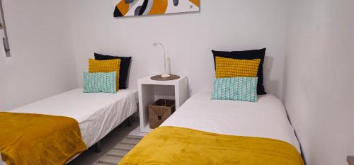 two beds in a room with yellow and blue pillows at Casa dos Sinos 2Bedroom Beach Apartment with Terrace in Albufeira