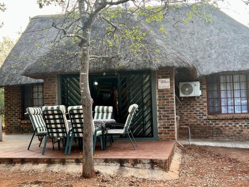 a house with chairs and a table on a deck at Tranquil Bush Cottage at Kruger in Marloth Park