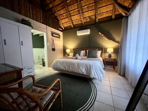a bedroom with a bed and a chair in a room at Tranquil Bush Cottage at Kruger in Marloth Park