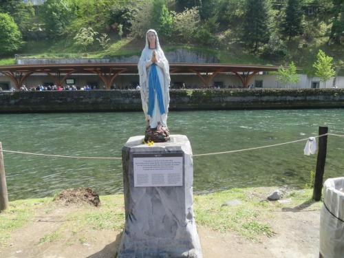a statue of a woman standing on a rock next to a river at Bernadette' Cosy Flat - 3 minutes walk main door to sanctuary entrance- Old Town - Bernadette de Soubirous's neighborhood - Chapel for Prayer on site in Lourdes