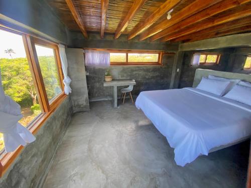 a bedroom with a bed and a desk and windows at Hermanos Perdidos Surf in Las Tunas
