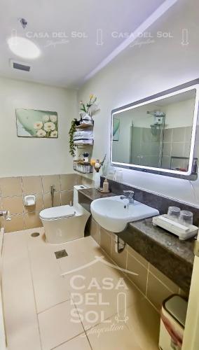 a bathroom with a toilet and a sink and a mirror at Casa Del Sol Staycation in Manila