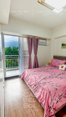 a bedroom with a pink bed and a window at Casa Del Sol Staycation in Manila