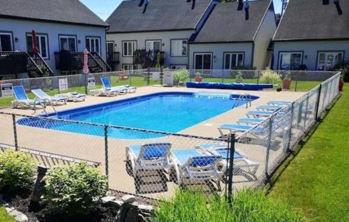 a fence with chairs and a swimming pool at Le Repère du Mont-Saint-Anne in Beaupré