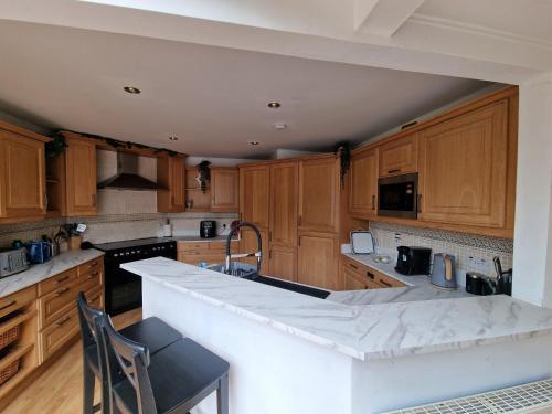 une cuisine avec des armoires en bois et un comptoir blanc dans l'établissement WATERSIDE 3 BED COTTAGE, HOT TUB, SAUNA, PVT BEACH, à Arrochar