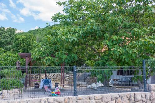 a fence with toys in front of a tree at Apartments Sanja in Karlobag
