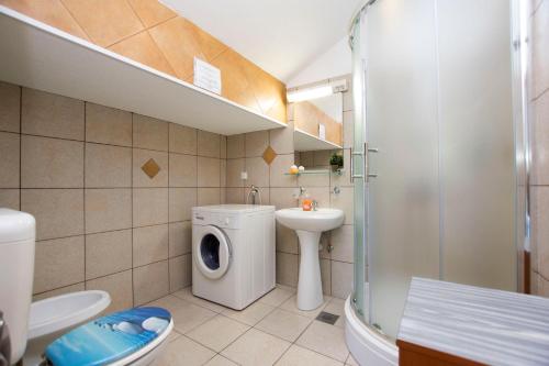 a bathroom with a toilet a sink and a washing machine at Apartments Sanja in Karlobag