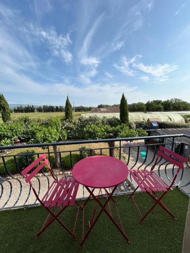 a pink table and two chairs on a balcony at Domaine Les feuilles de Chêne in Carpentras