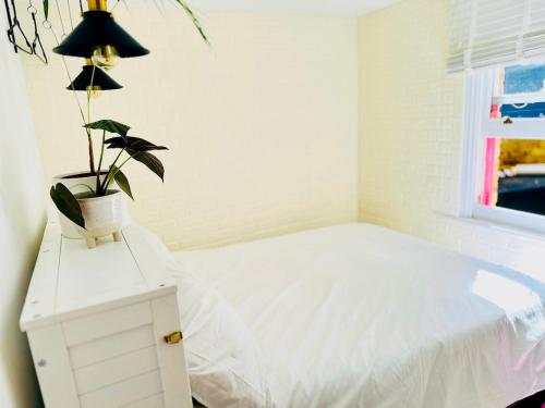 a bedroom with a bed and a potted plant at Bay escape beach apartment steps from the sea in Herne Bay