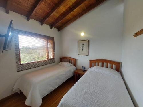 two beds in a room with a window at Hotel Campestre Ronda Ecuestre Rionegro in La Ceja