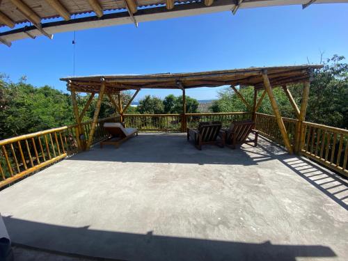 a deck with two chairs and a pergola at Hermanos Perdidos Surf in Las Tunas