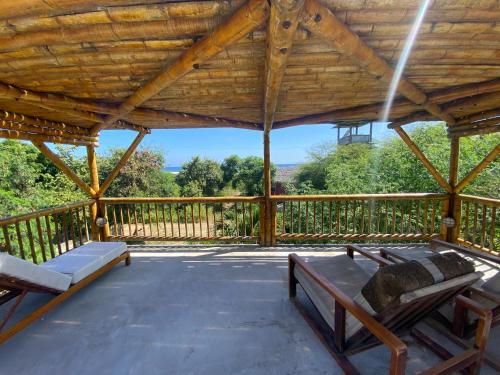 a porch with a wooden roof with two benches at Hermanos Perdidos Surf in Las Tunas