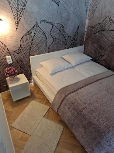 a bedroom with a bed with a wall with leaves at Apartament Pod Malnikiem in Muszyna